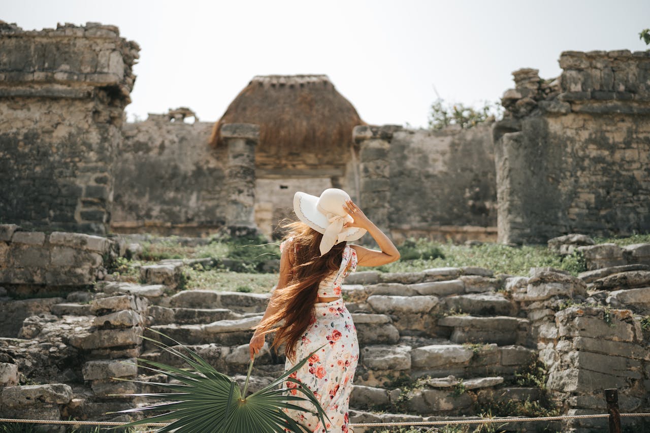 A woman in a floral dress explores the ancient Tulum ruins in Mexico during summer.
